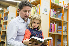 Ein Mann und ein Kind schauen gemeinsam ein Buch an.