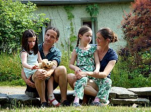 Gerlinde und Andreas Feller sitzen mit ihren zwei Töchtern auf dem Grundstück
