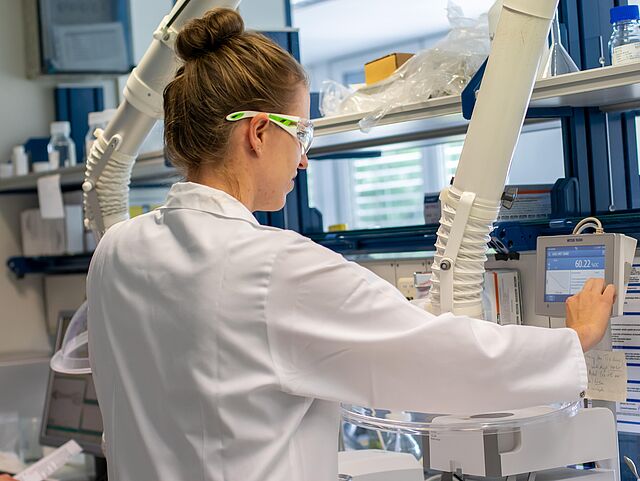 Eine Mitarbeiterin mit Schutzbrille im Labor