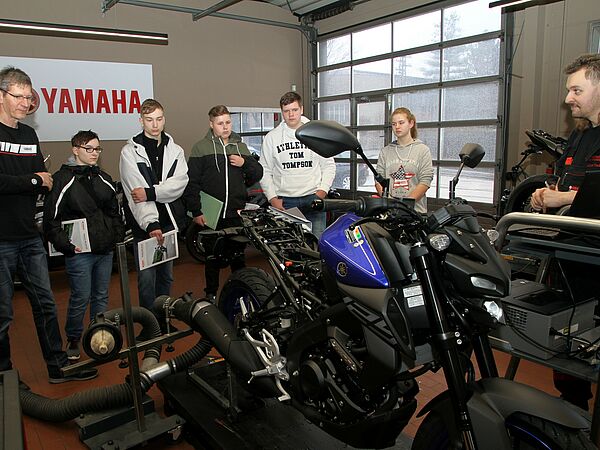 Jugendliche informieren sich über Ausbildungsmöglichkeiten in einer Motorradwerkstatt