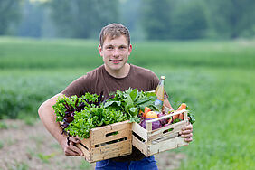 Daniel Hausmann zeigt frische Bio Obst- und Gemüsekisten.