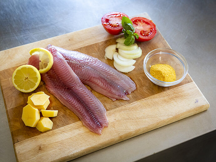 Frischer Fisch auf Holzplatte mit Zitrone und Salat